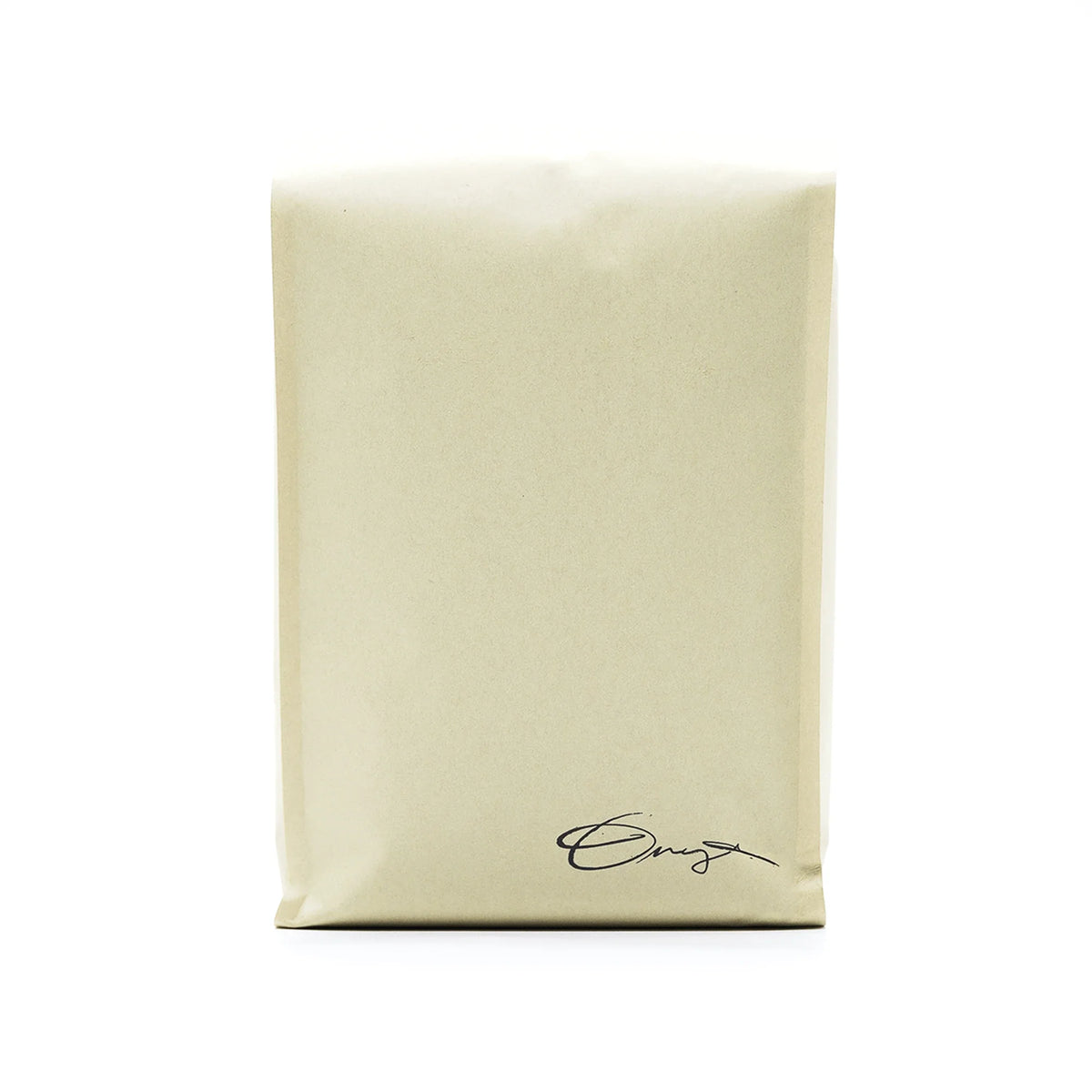 A beige Monarch bag by Onyx Coffee Lab with a small cursive logo and dark chocolate coffee notes.